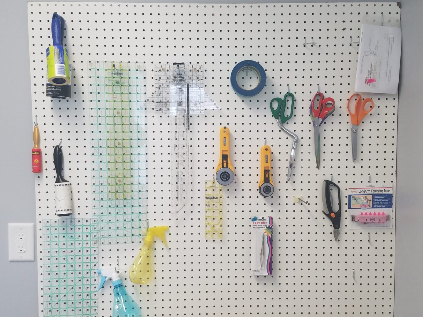 A white pegboard with many different items hanging on it.
