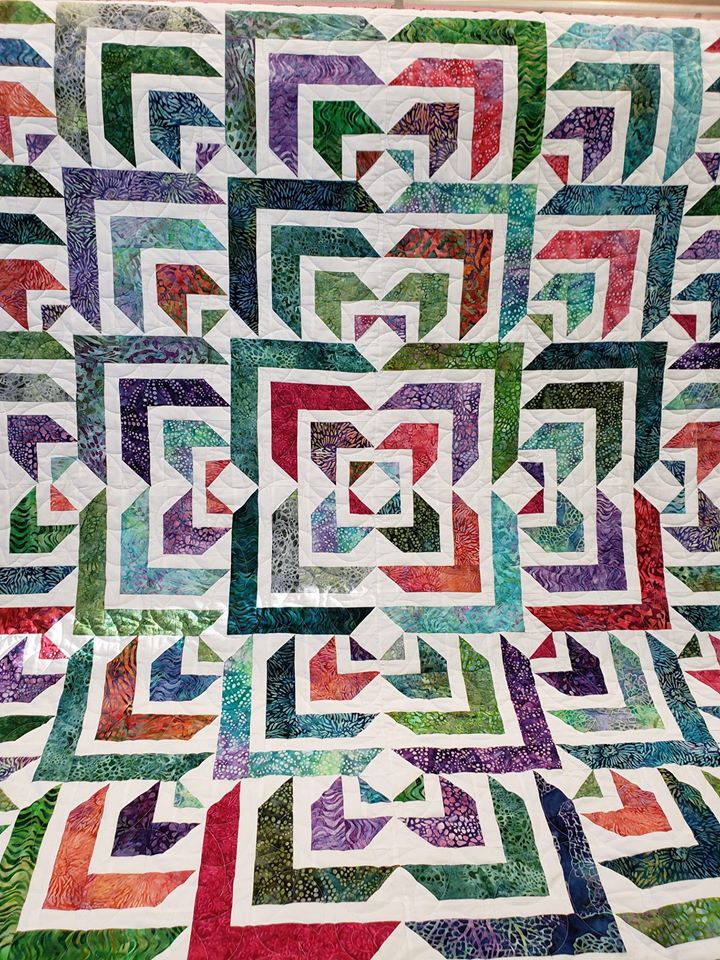 A quilt with squares and triangles in the middle.