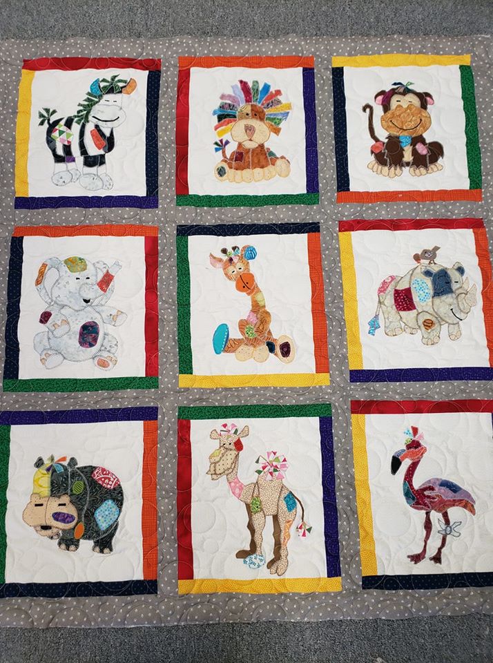 A quilt with nine different animals drawn on it.