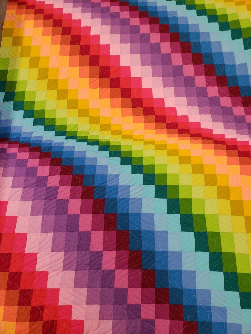 A rainbow colored quilt with a colorful background.