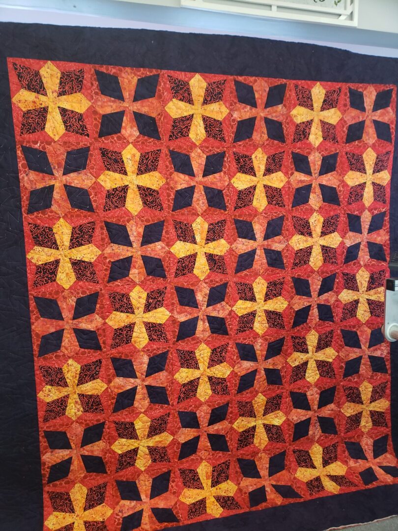 A quilt that is made of red and yellow fabric.